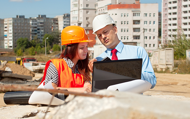 Woman and man using computer on construction site