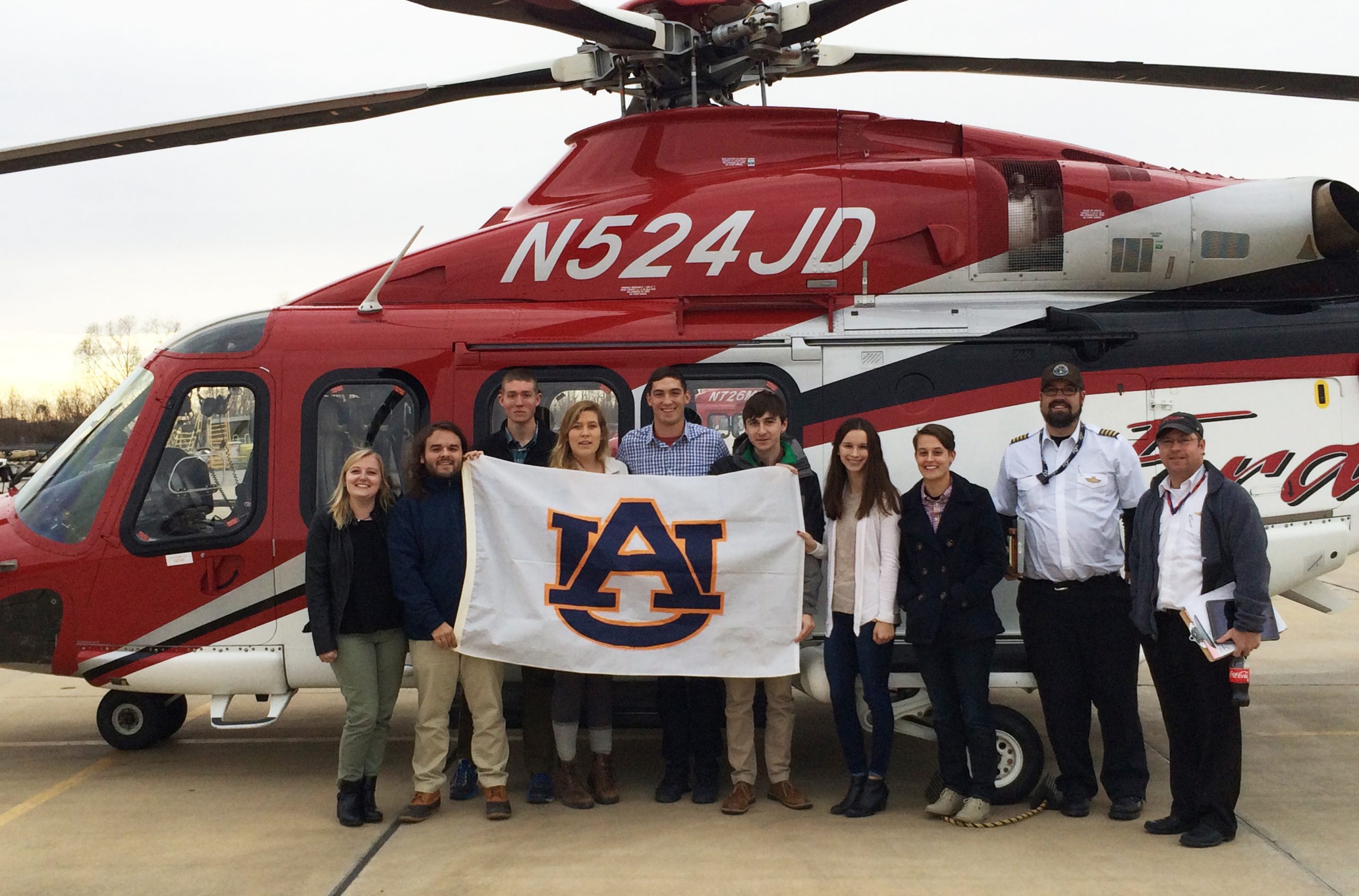 students holding AU sign with helicopter