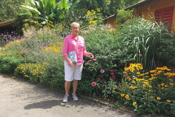 Cyndi in front of a flourishing garden