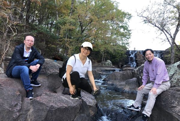 Left to right: Shi, Pan, Tian sitting on rocks in front of waterfalls at Chewacla State Park in Auburn, AL.